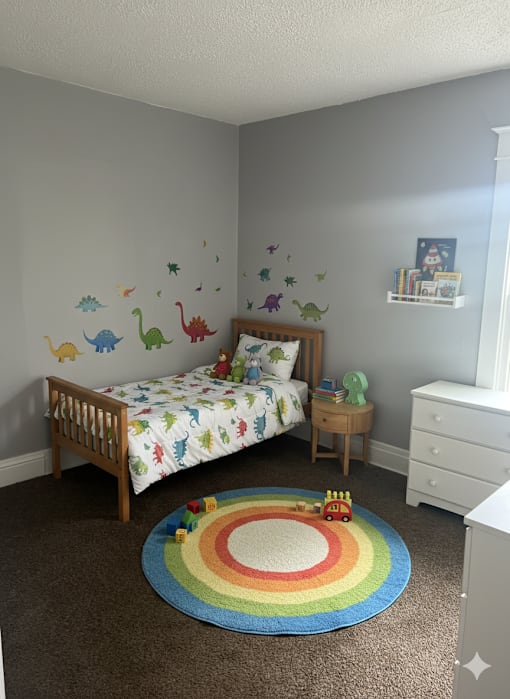 A child's bedroom with a rainbow rug and dinosaur wall decals.