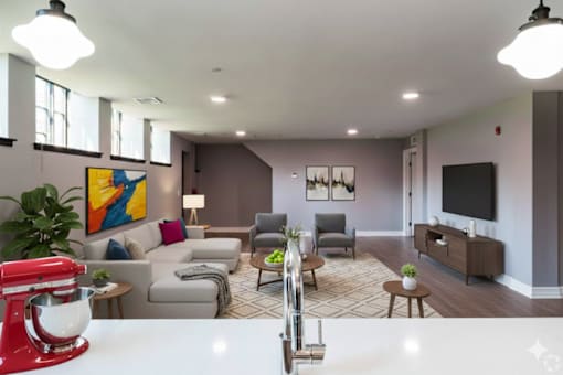 A red kitchenaid mixer sits on a white countertop in a modern living room.