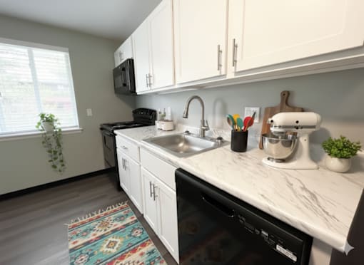 A kitchen with a black dishwasher and white cabinets. at Highview Manor Apartments, Fairport, NY, 14450