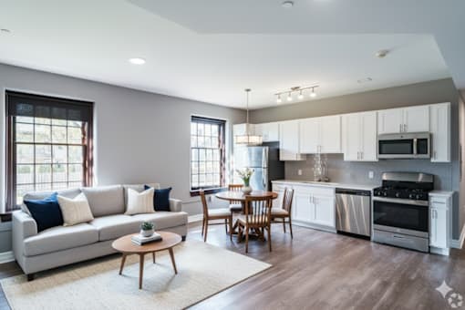 A modern kitchen with a grey couch and wooden chairs.