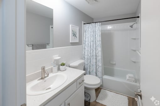 A white bathroom with a sink, toilet, and shower.