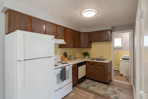 A kitchen with white appliances and wooden cabinets.