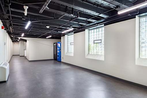 A large, empty room with a blue door and windows on the wall.