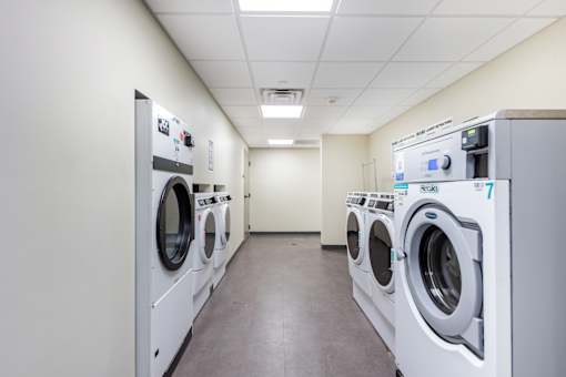 A row of industrial washing machines are lined up in a clean, empty room.