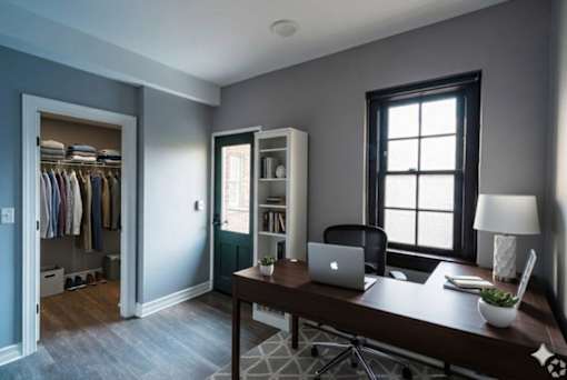 A room with a desk, chair, and a laptop.