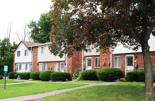 a picture of a brick apartment building with a sidewalk in front of it
