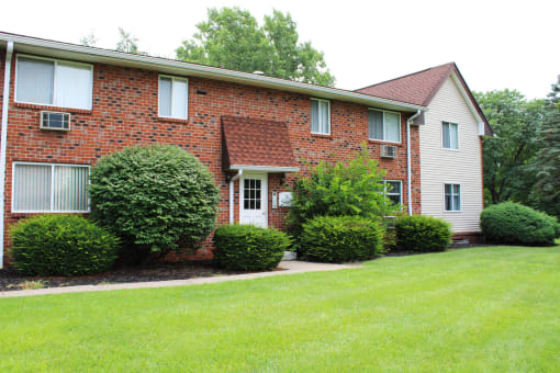 a red brick house with white siding and a green lawn