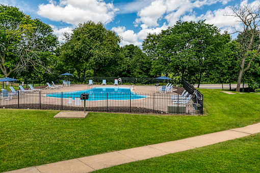 A pool surrounded by a fence and trees.