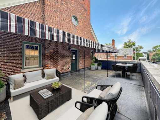 A patio with a table and chairs is set up outside a brick building.
