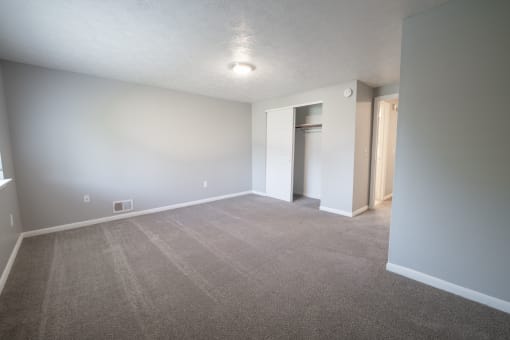 an empty living room with gray carpet and white walls at Willowbrooke Apartments, Brockport, New York