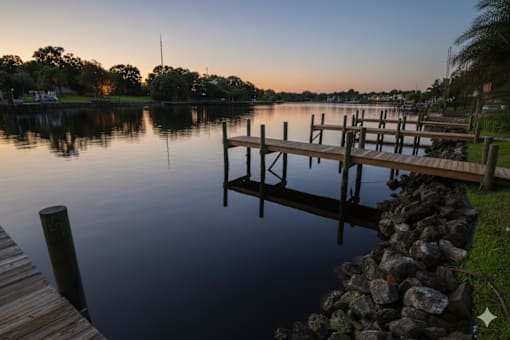 A dock extends into a calm body of water at sunset.