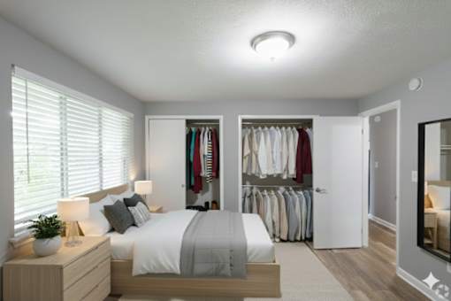 A bedroom with a bed, nightstand, and closet.