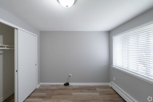 an empty room with a large window and a closet