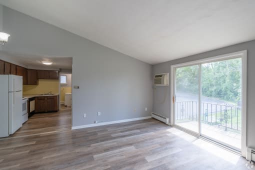 an empty living room and kitchen with a sliding glass door
