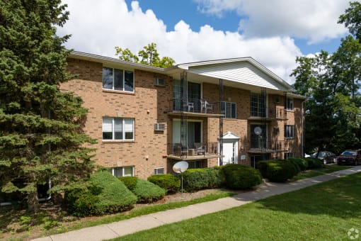 the exterior of a brick apartment building with a sidewalk
