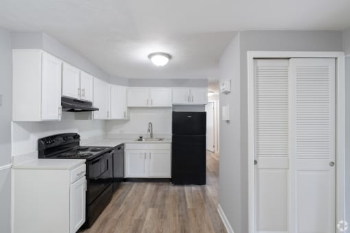 an empty kitchen with white cabinets and black appliances
