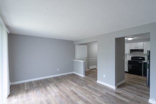 an empty living room with wood floors and a kitchen
