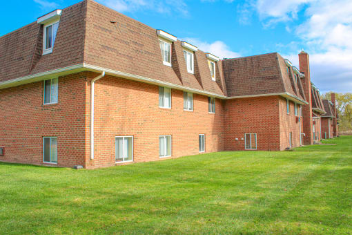 a large brick building with a green lawn at Willowbrooke Apartments, Brockport, 14420