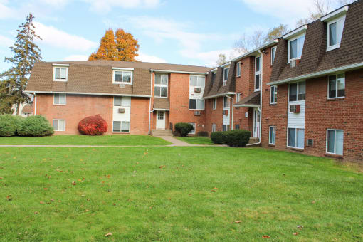 an apartment complex with a green lawn and a sidewalk at Willowbrooke Apartments, Brockport, New York