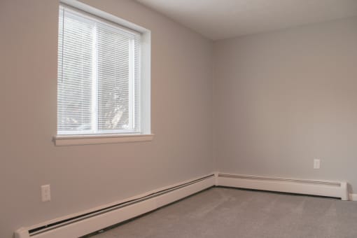 the corner of a room with a large window and a white baseboard at Willowbrooke Apartments, Brockport, New York