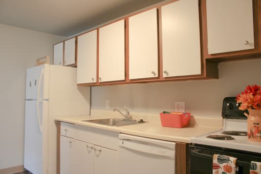 a kitchen with white cabinets and a sink and a refrigerator at Willowbrooke Apartments, Brockport, 14420