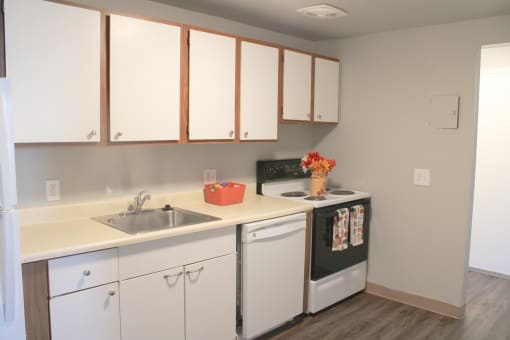 a kitchen with white cabinets and a sink and a stove at Willowbrooke Apartments, Brockport, NY