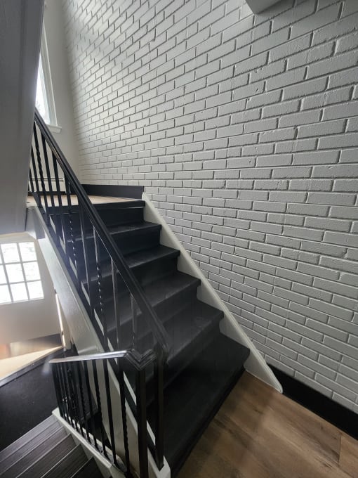 a staircase with black stairs and a white brick wall