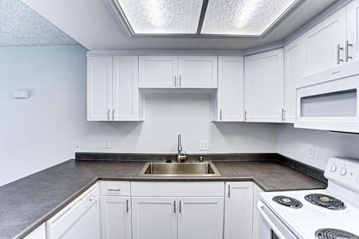 A kitchen with white cabinets and a stove top oven.