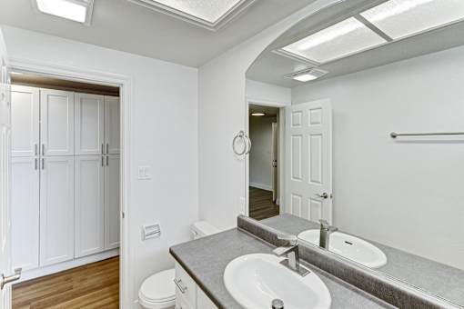 A bathroom with a toilet, sink, and mirror.