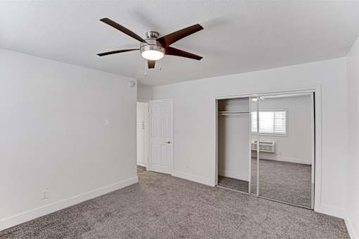 A room with a ceiling fan and a carpeted floor.