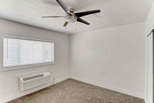A room with a ceiling fan and a window with blinds.