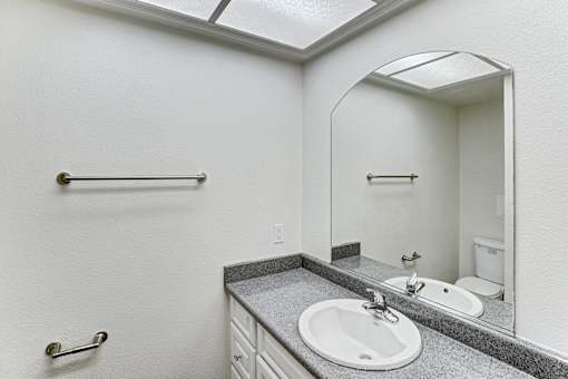 A bathroom with a sink, mirror, and towel rack.