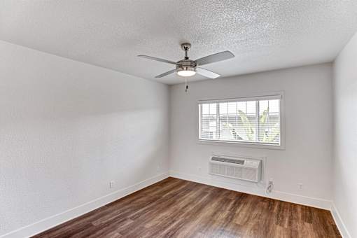 A room with a ceiling fan and a window with blinds.