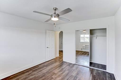 A room with a ceiling fan and wooden floors.