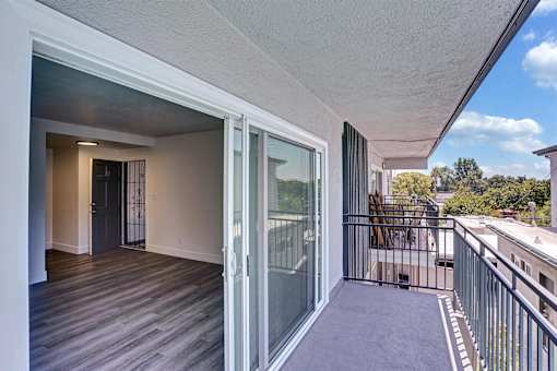 A second floor balcony with a glass door leading to a room.