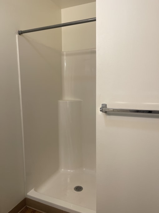a bathtub with a silver handle and a white wall in the background