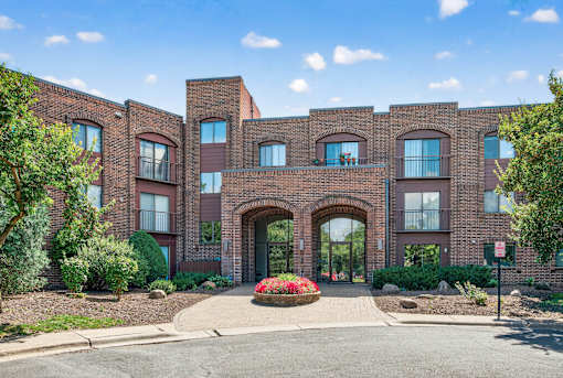 A red brick building with a large arched entrance and a small garden in front.