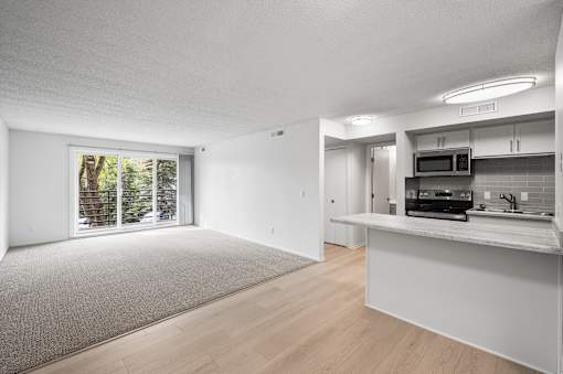 an empty living room and kitchen with a door to a patio