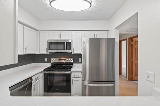 A modern kitchen with stainless steel appliances and white cabinets.
