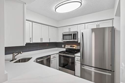 A modern kitchen with stainless steel appliances and white cabinetry.