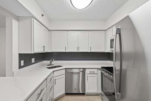 A kitchen with white cabinets and a black backsplash.