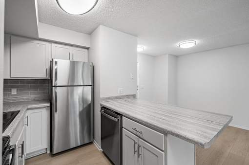 a kitchen with white cabinets and a stainless steel refrigerator