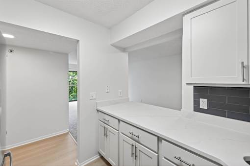 A kitchen with white cabinets and a white counter top.