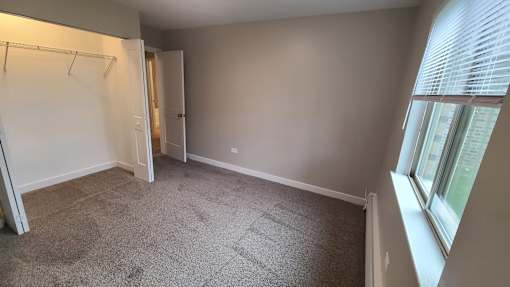 an empty room with a closet and a window