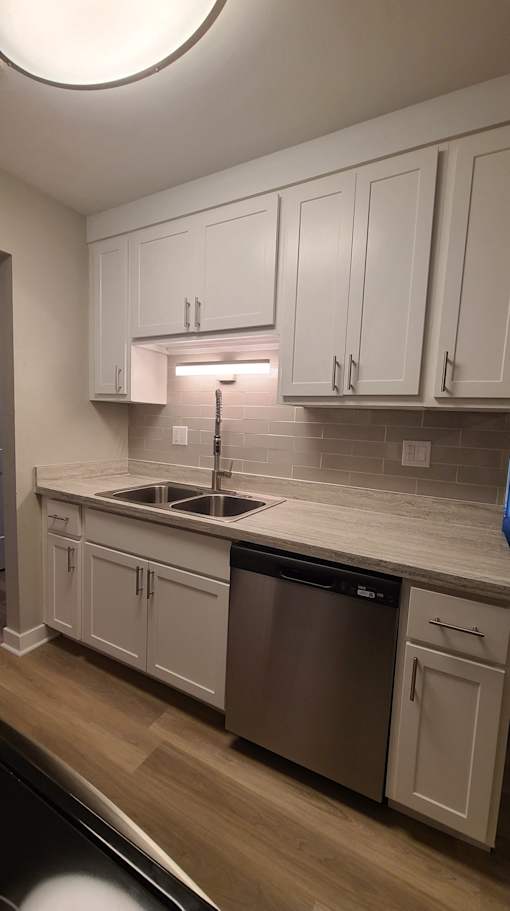 Rehabbed kitchen with white cabinets and glass backsplash