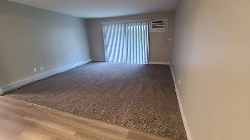 a living room with a window and a carpeted floor