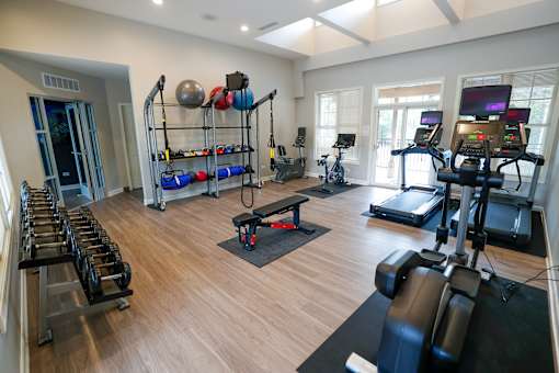 A gym with a variety of equipment including treadmills, weights, and exercise machines.