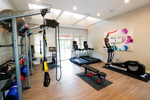A gym with a variety of equipment including a treadmill, rowing machine, and weight machines.