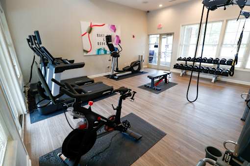 A gym with a variety of equipment including treadmills, weights, and exercise bikes.