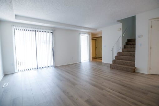 an empty living room with wood floors and a staircase